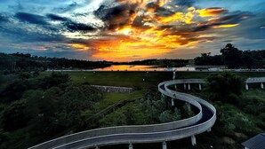 A curved bridge over a body of water with a sunset in the background. - GuanLu Art hotel (Guangzhou)