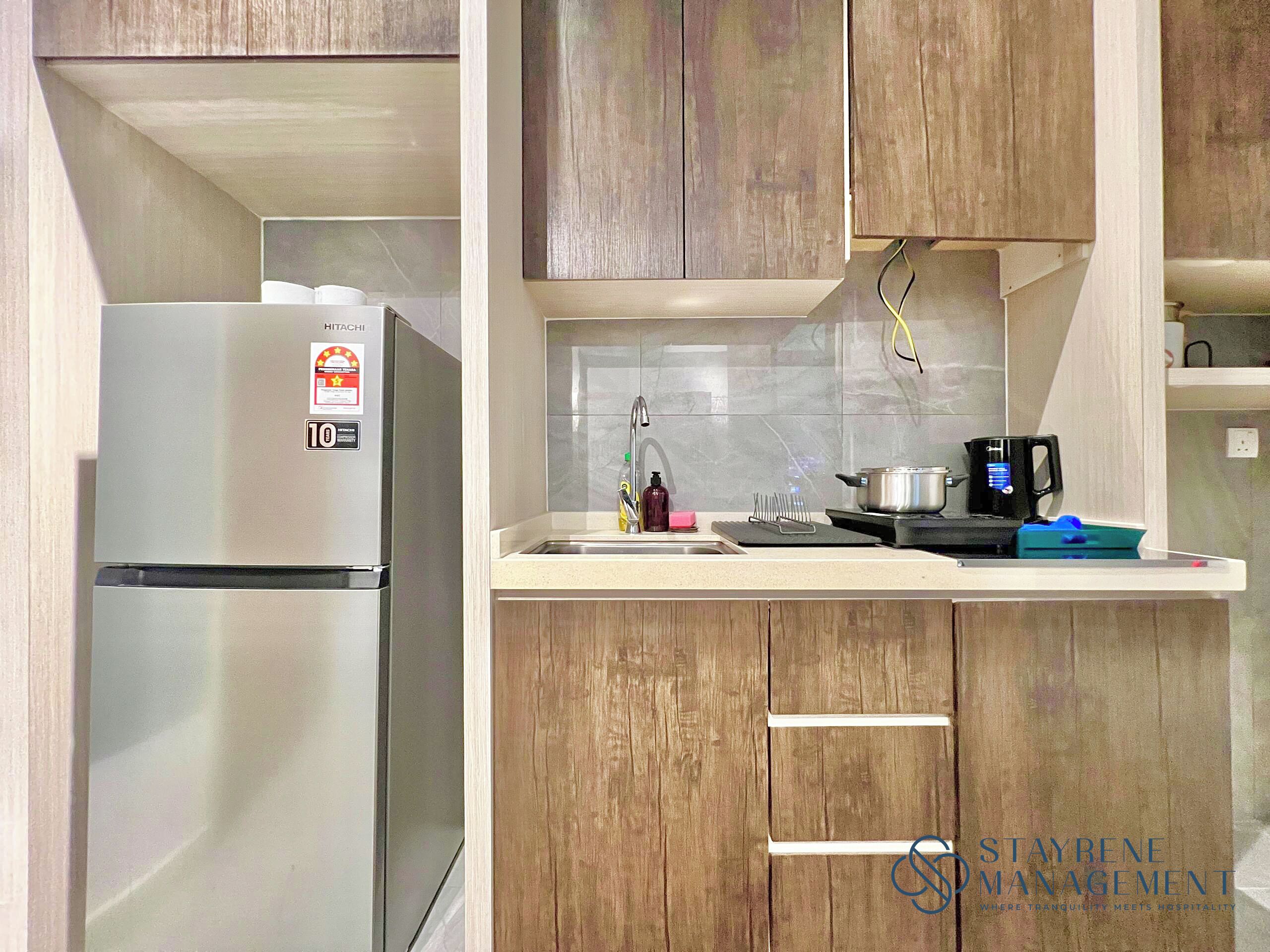 A compact kitchen with a stainless steel refrigerator, a sink, and a stove.