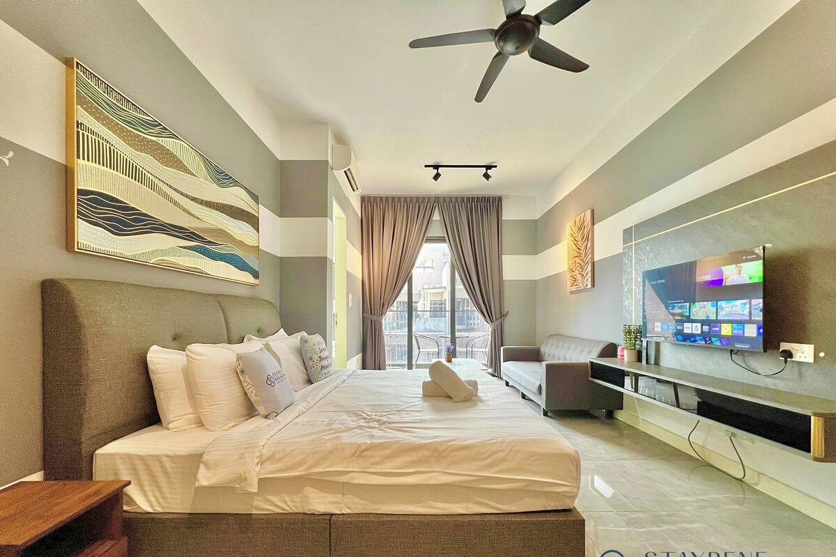 Een moderne hotelkamer met een groot bed, een flatscreen televisie, een plafondventilator en uitzicht op de stad door grote ramen.
