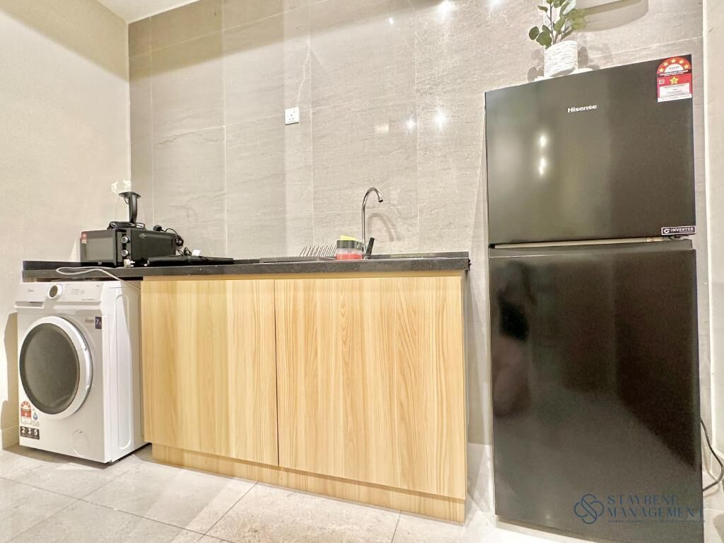 Een kleine keuken met een wasmachine, een koelkast en een houten kast.
