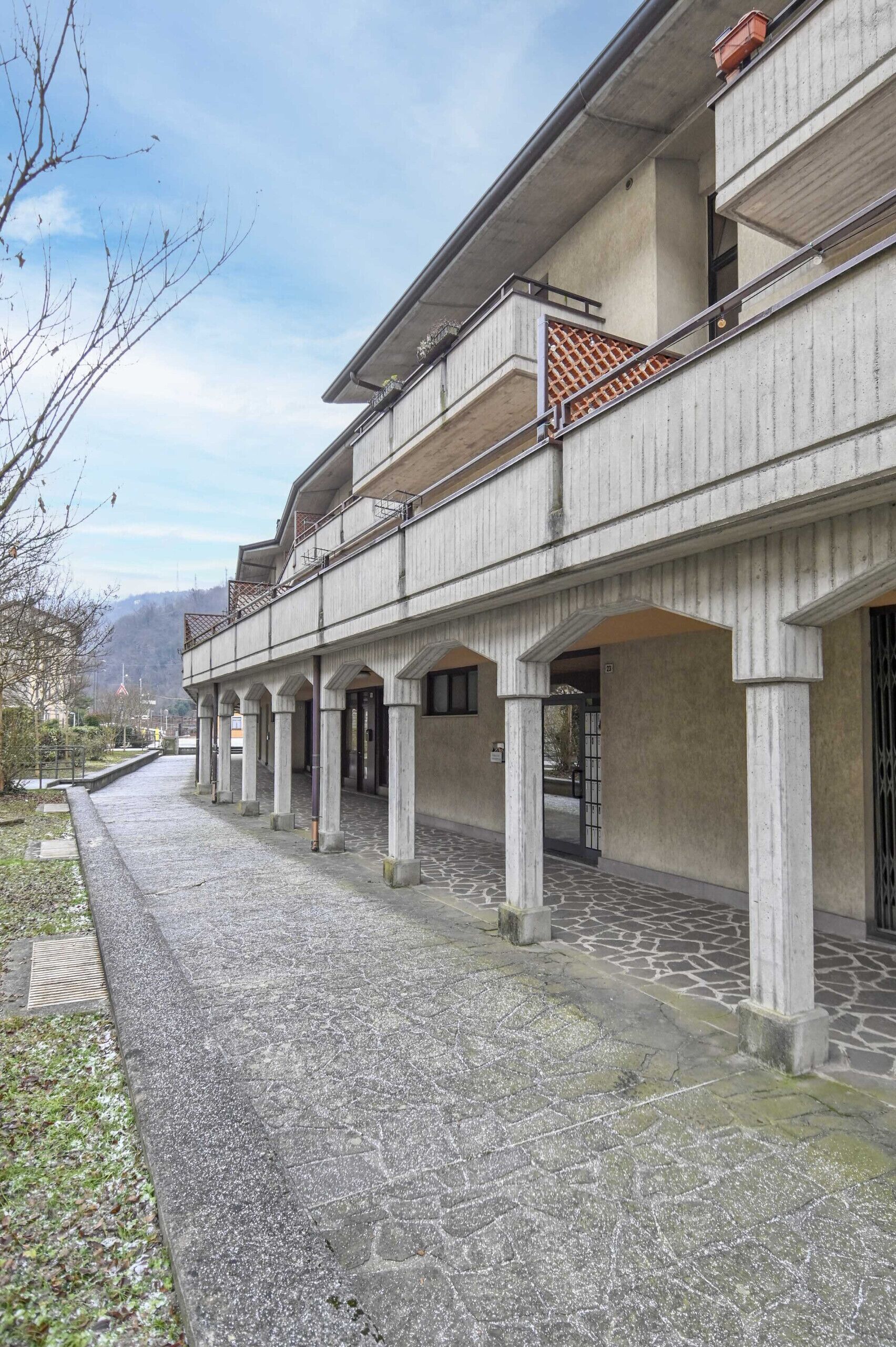 A building with a covered walkway, columns, and balconies.