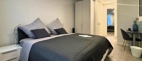 Un dormitorio moderno con una cama grande, un escritorio y un armario.