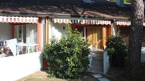 Una casa con tetto in tegole, un portico coperto e un piccolo giardino.
