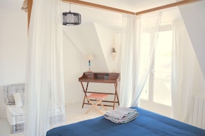 Une chambre à coucher avec un lit, un bureau, une chaise et une fenêtre avec des rideaux.