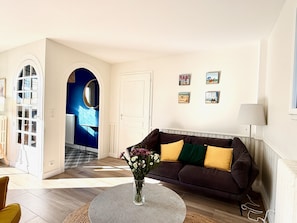 A living room with a sofa, a round coffee table with flowers, and a lamp. - Villa Amaryves à La Baule (La Baule-Escoublac)