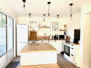 A modern kitchen with a central island, white cabinetry, and pendant lighting. - Villa Amaryves à La Baule (La Baule-Escoublac)