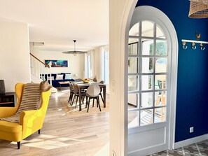 A modern living room with a yellow armchair, a dining area with a table and chairs, and a large arched window. - Villa Amaryves à La Baule (La Baule-Escoublac)