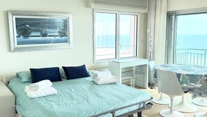 A hotel room with a bed, a desk, a chair, and a large window with a view of the sea. - Face mer à La Baule : Le Neptune (La Baule-Escoublac)