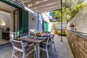 Un espace de restauration en plein air avec une table dressée pour deux personnes, des chaises et une variété de plats et de boissons.