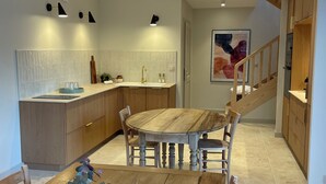 A modern kitchen with a wooden dining table, a vase of flowers, and a staircase leading to another level. - La Villa de Paul, a completely renovated 19th-century building in the Savoyard foreland (Yenne)