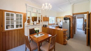 Une cuisine avec des meubles de rangement en bois, une table à manger avec des chaises et un lustre.