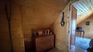 A wooden interior with a dresser, a wall-mounted lamp, and a door leading to another room.