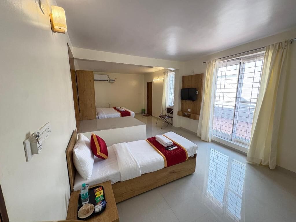 Une chambre d’hôtel avec deux lits, une télévision, une fenêtre avec des rideaux et une petite table avec des articles de toilette.