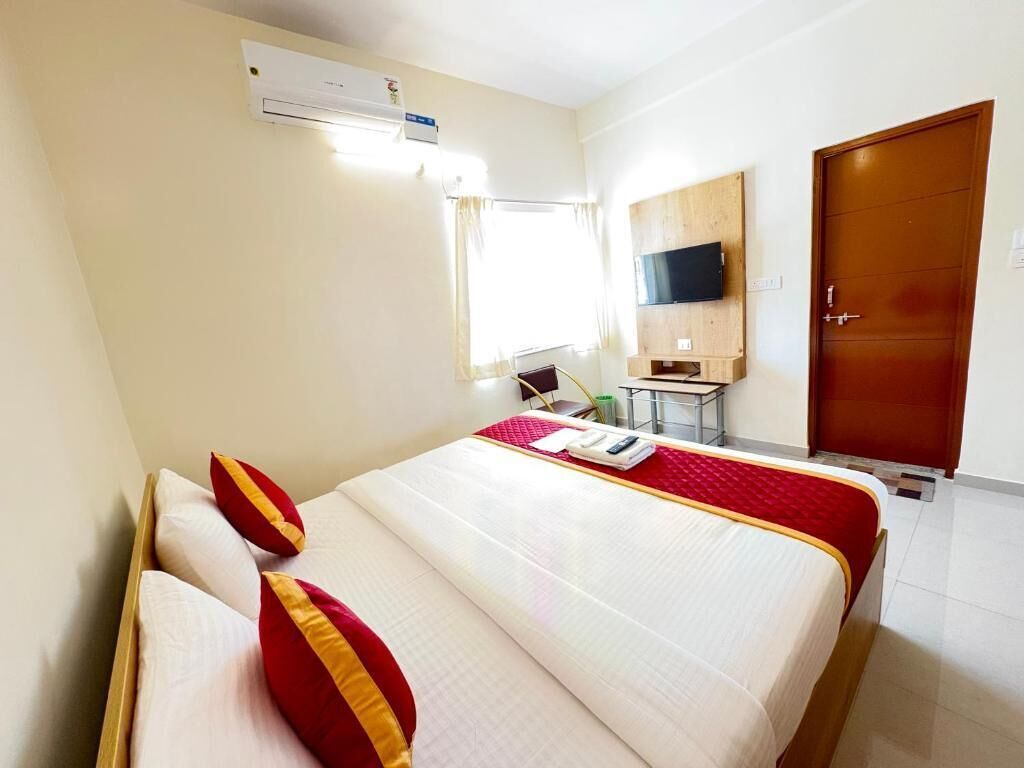 A hotel room with a bed, a TV mounted on the wall, a desk, and a wardrobe.
