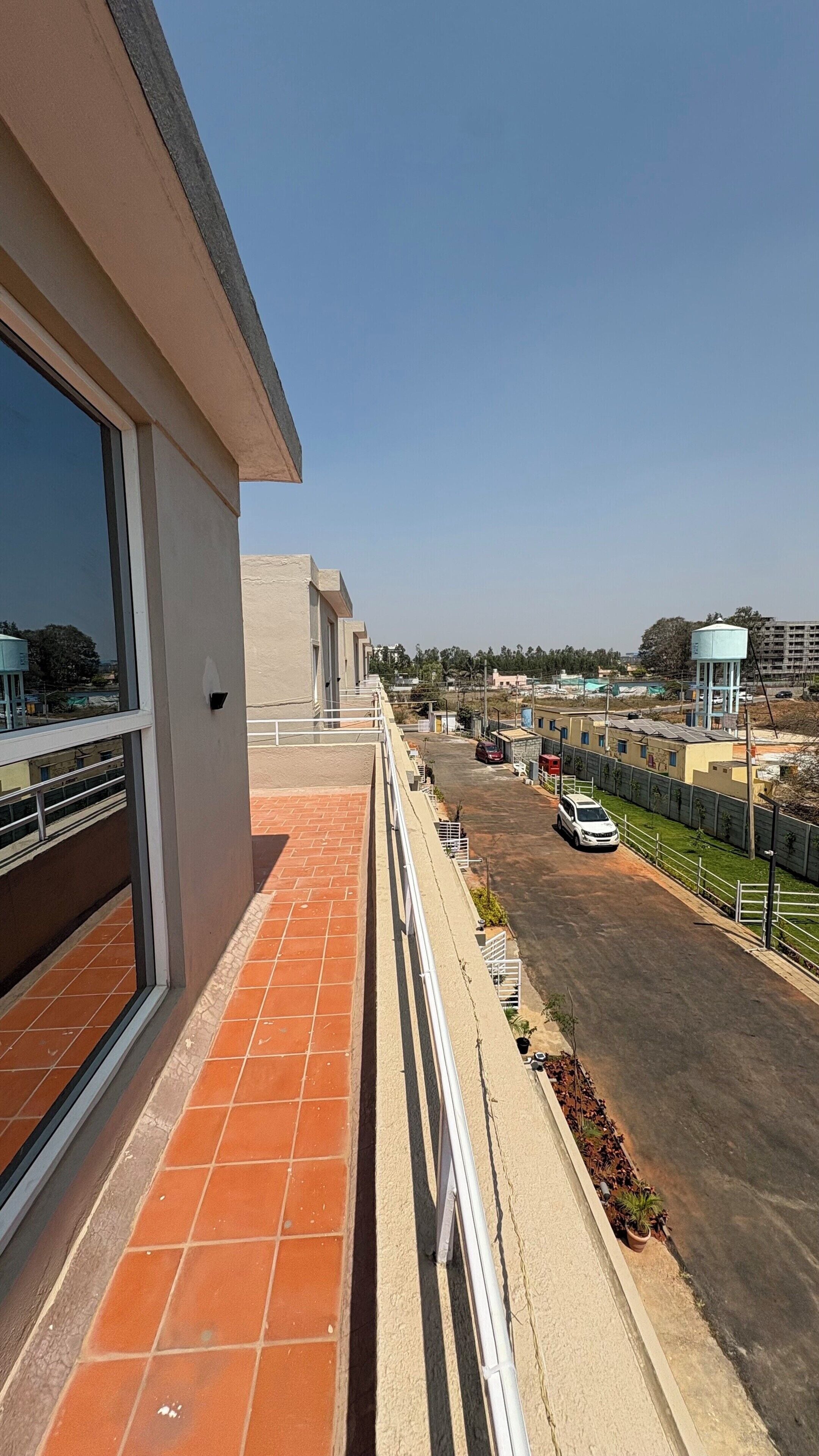 A balcony with a view of a parking area and distant buildings.