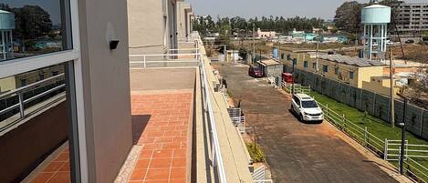 A balcony with a view of a parking area and distant buildings.