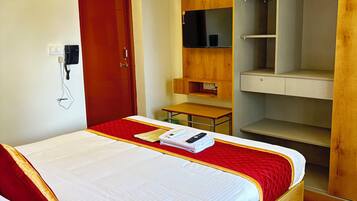Een hotelkamer met een bed, een houten garderobe en een bureau.