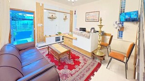 Un salon comprenant un canapé, une table basse, un téléviseur, un bureau et une lampe décorative.