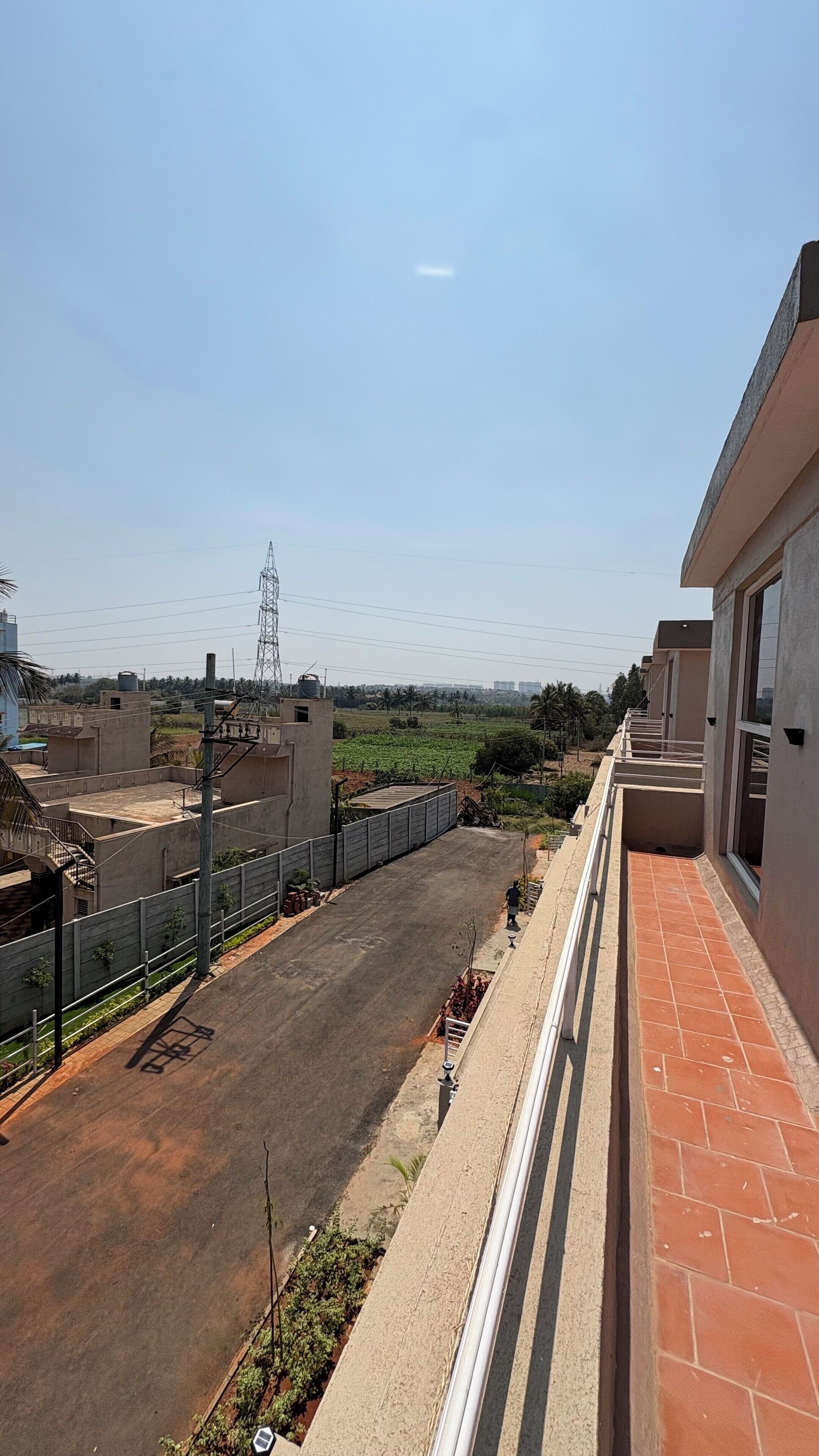 A residential area with a paved road, a fenced area, and buildings with balconies.
