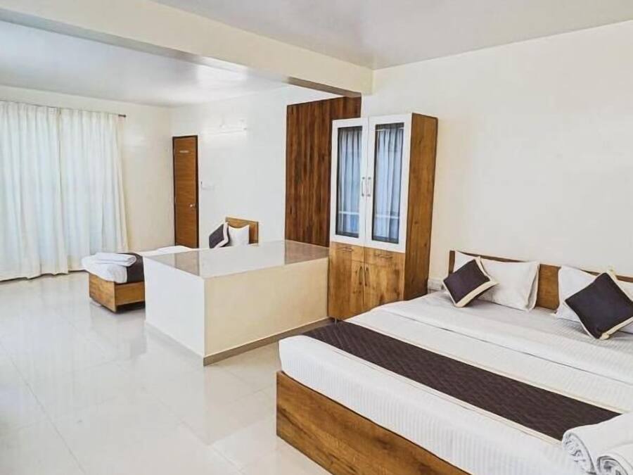 Quarto de hotel moderno com uma cama grande, um espaço de estar separado e uma parede de destaque em madeira.