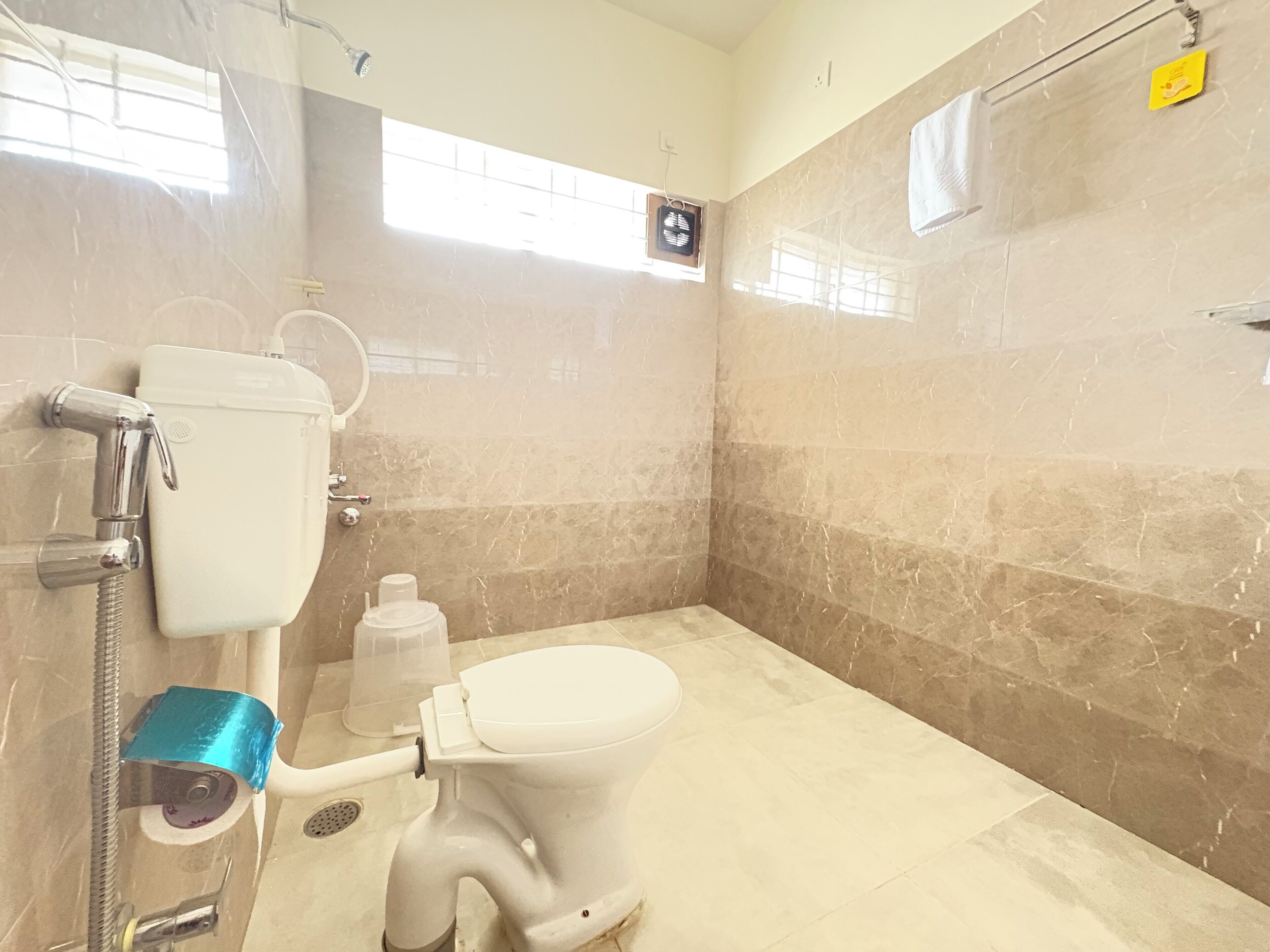A bathroom with a toilet, shower, and a marble wall.