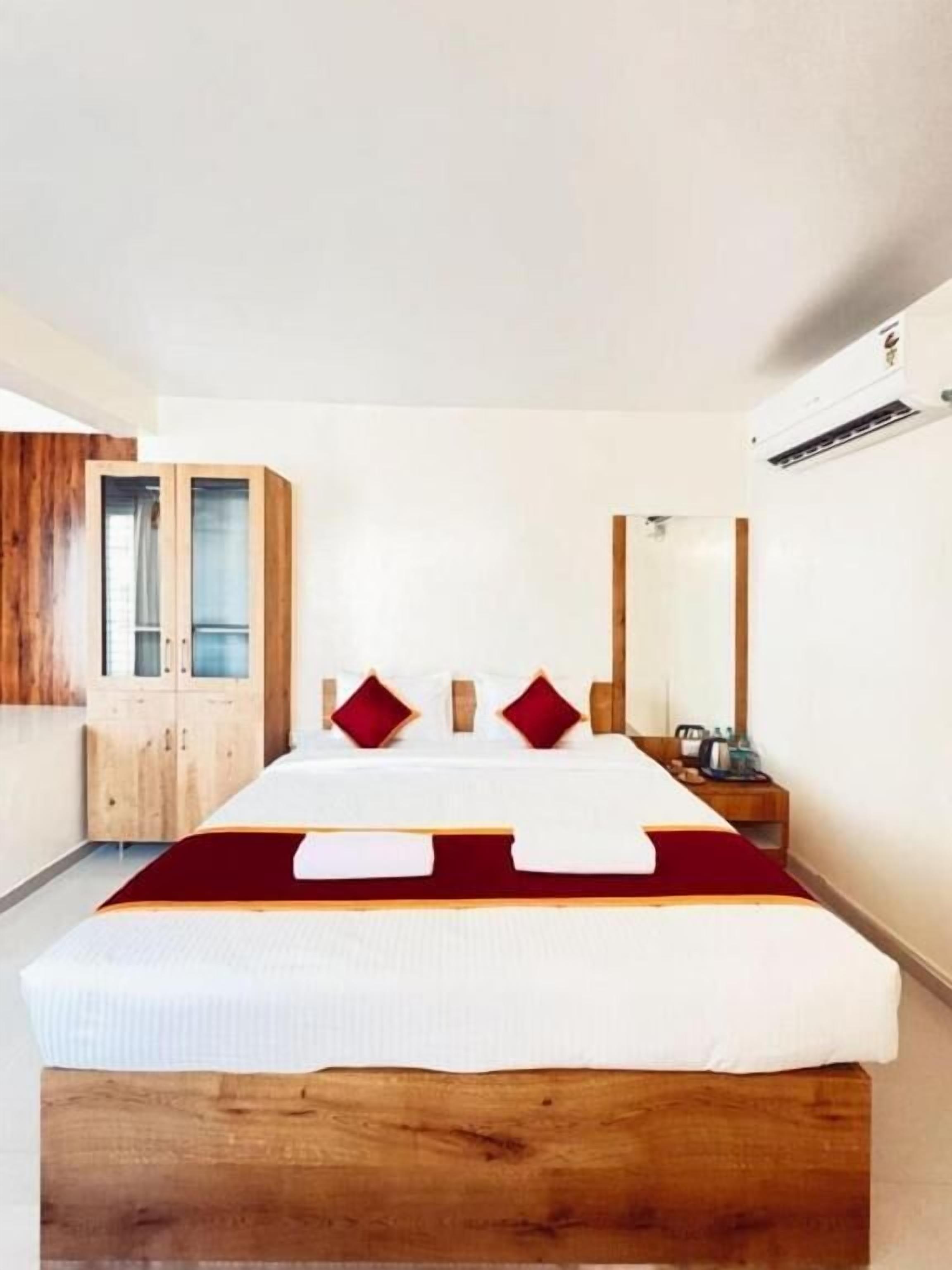 Un dormitorio con cabecera de cama de madera, un armario, una mesita de noche y un equipo de aire acondicionado.