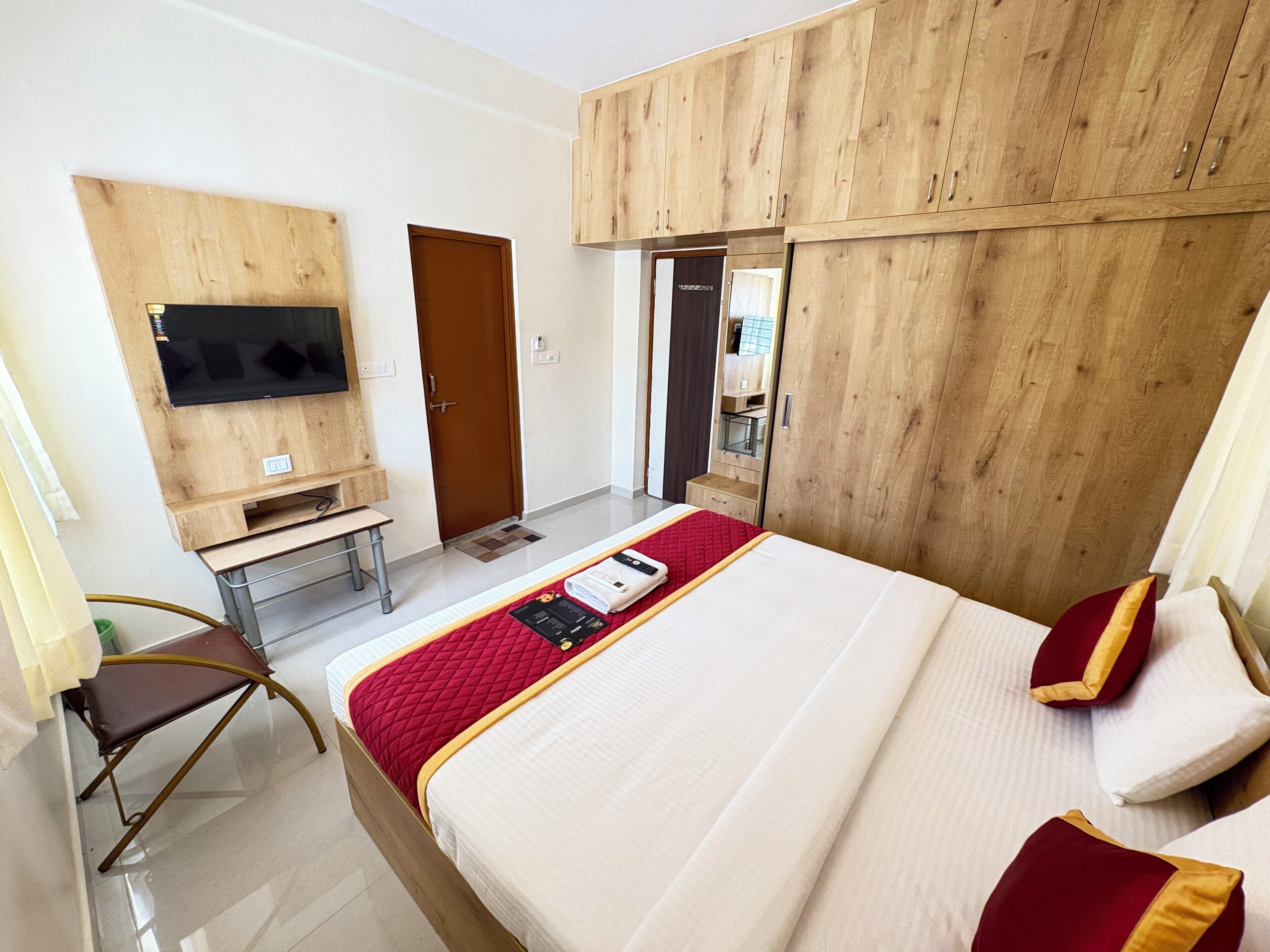 A hotel room with a bed, a desk, a television, and a wardrobe.