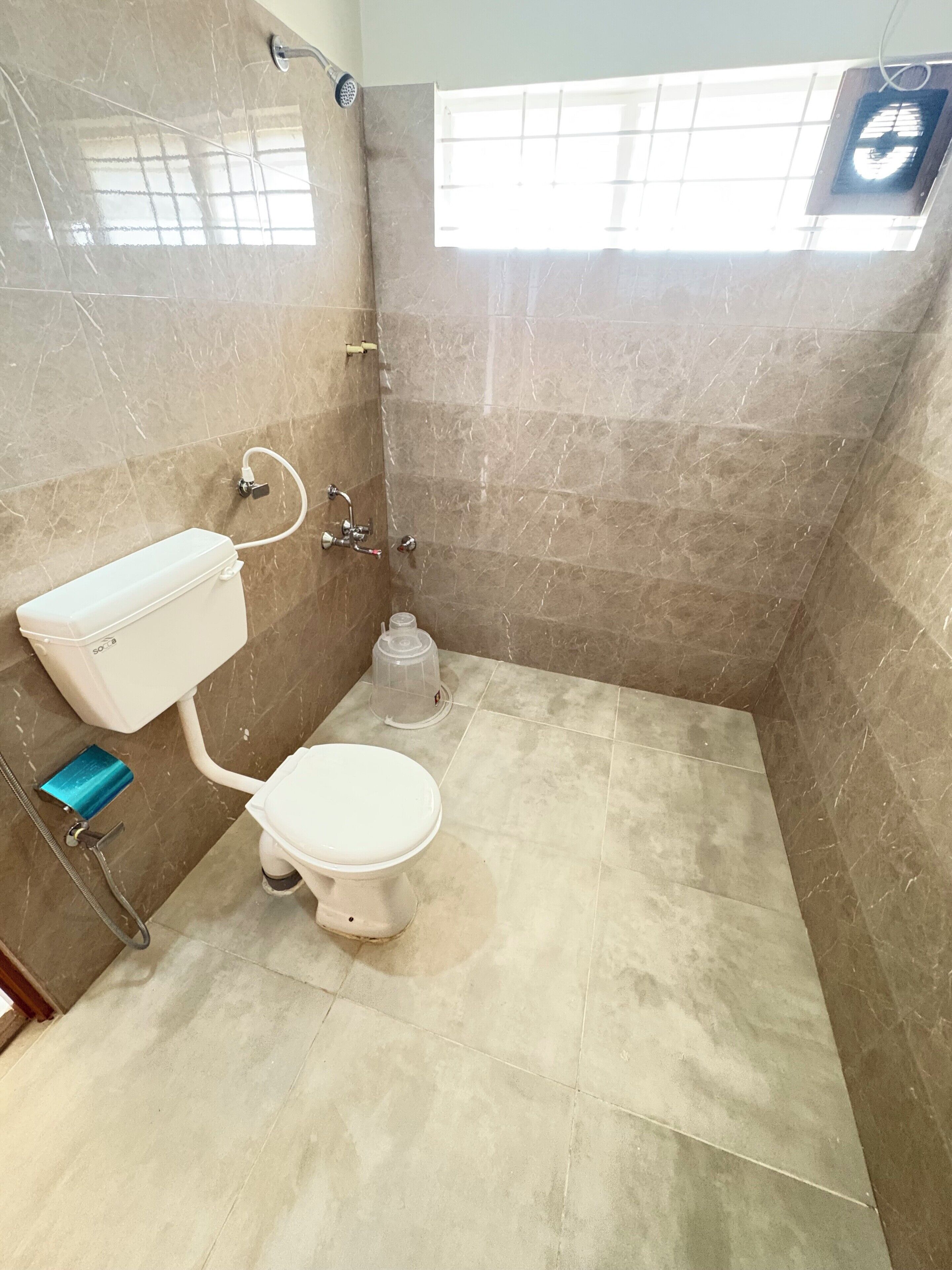 Een badkamer met toilet, douche en een boiler.