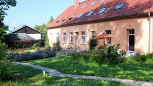 Et toetagers hus med rødt tegltag, en have med forskellige planter, og en sti der fører til indgangen.