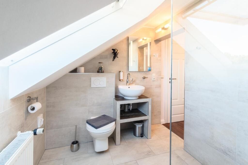 A modern bathroom with a white sink, toilet, and shower.