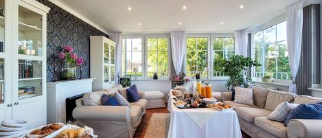 Ein geräumiges Wohnzimmer mit Kamin, zwei Sofas, einem Couchtisch und einem für das Frühstück gedeckten Esstisch.
