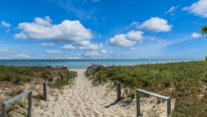 A sandy beach path leading to a beach with a clear sky and distant land. - Hotel Villa Wahnfried (Monchgut-Granitz)