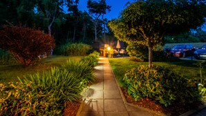 A pathway leading to a building with a porch, surrounded by greenery and a parked car. - Hotel Villa Wahnfried (Monchgut-Granitz)