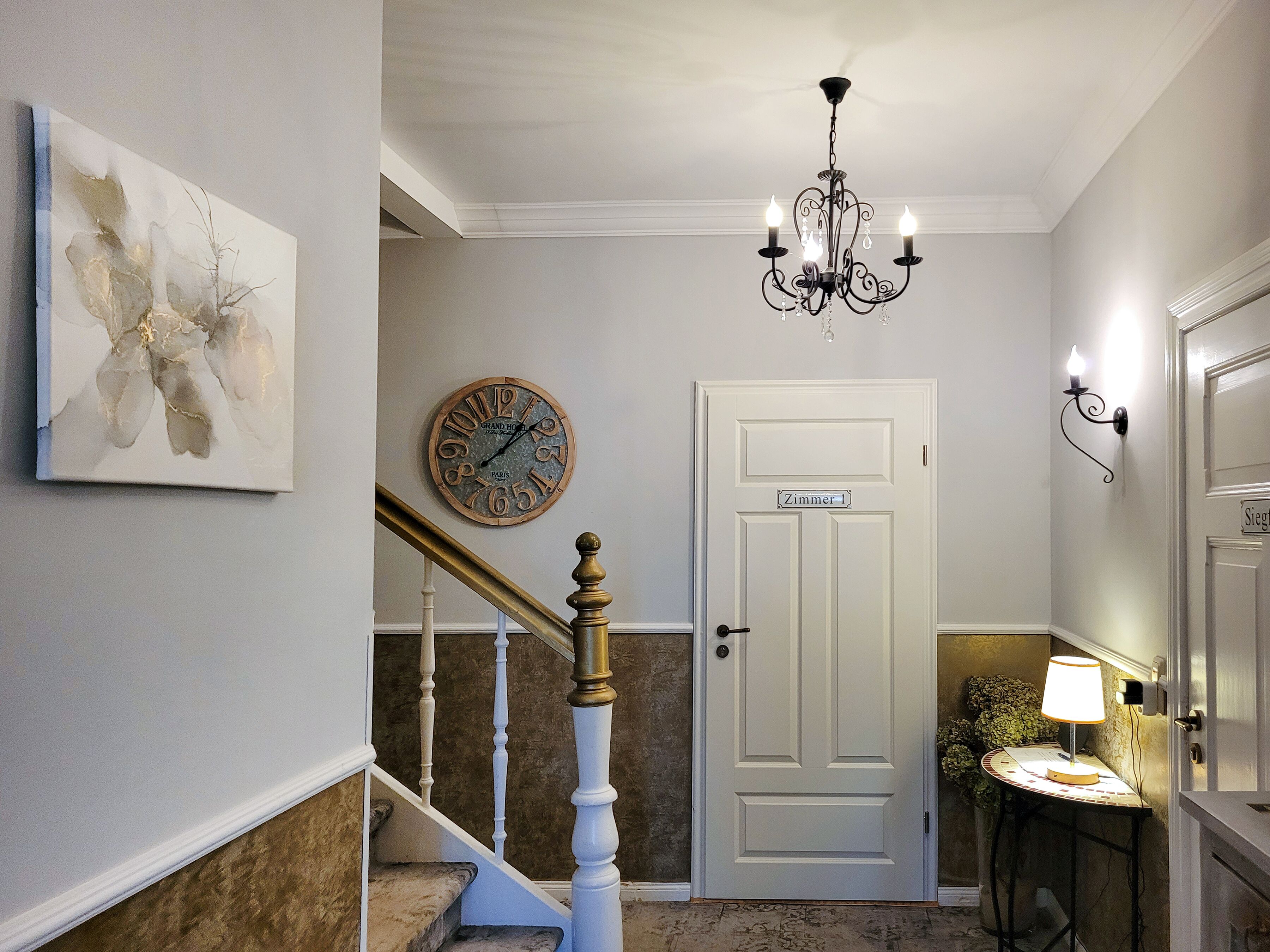 A staircase with a white door labeled 'Zimmer' and a wall clock.