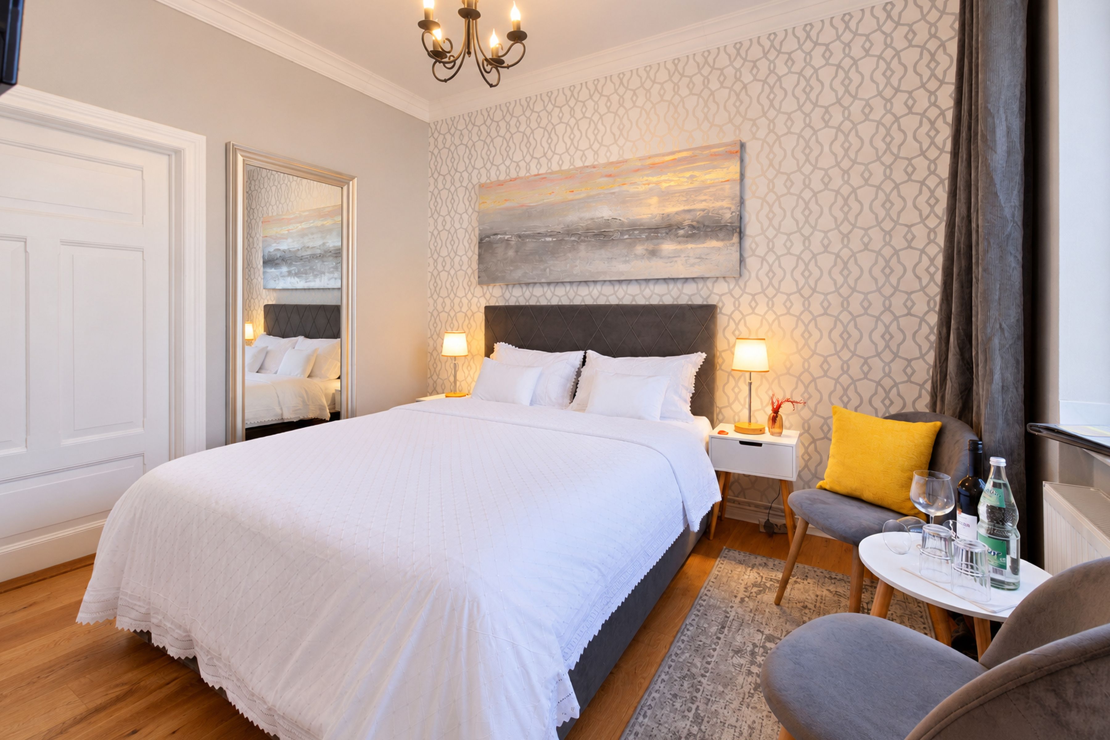A hotel room with a large bed, bedside tables, a chair, and a painting on the wall.