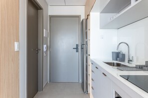 Una cocina moderna con un refrigerador de acero inoxidable, un horno empotrado y un lavamanos con un grifo contemporáneo.