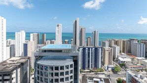 Um edif ício alto com piscina no terraço e vista para o oceano.