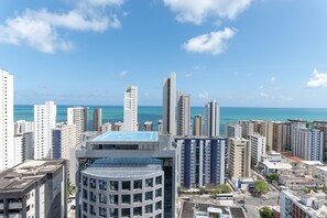 Um edifício alto com piscina no terraço e vista para o oceano.