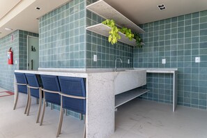 Une salle de bain moderne avec un grand lavabo, deux chaises bleues et des plantes vertes accrochées au mur.