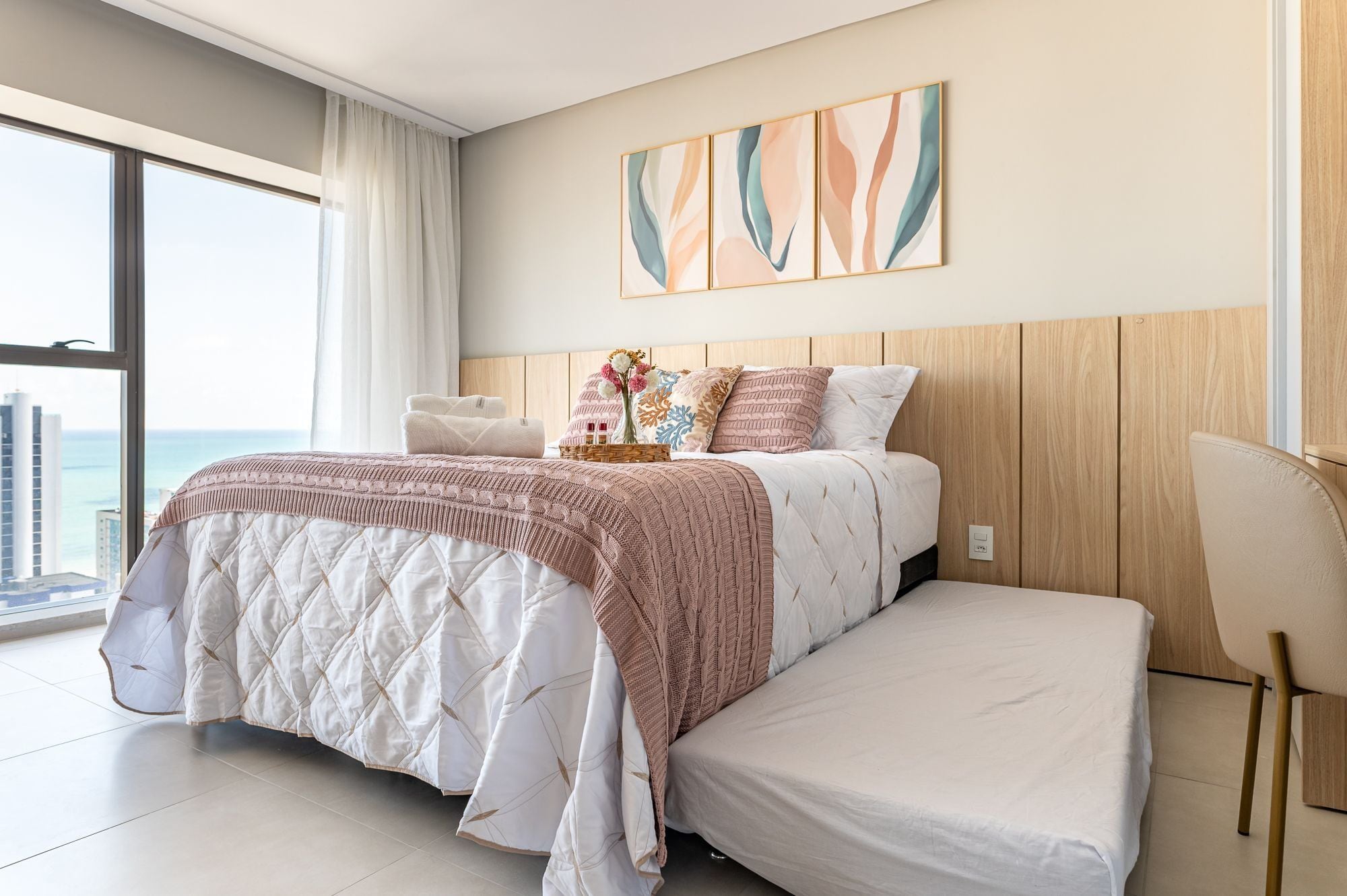 Ein modernes Schlafzimmer mit einem großen Bett, einer Sitzbank und Blick auf die Stadt.