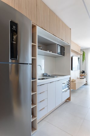 Une cuisine moderne dotée d’appareils électroménagers en acier inoxydable, de meubles en bois et d’un four à micro-ondes encastré.