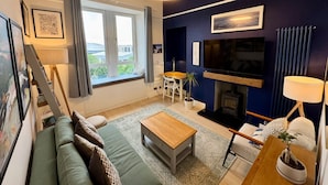 A modern living room with a sofa, coffee table, and a fireplace. - Warm, Upgraded Top-floor Flat in Finnieston (Glasgow)