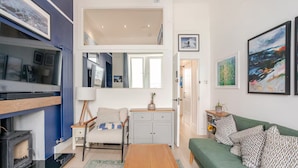 A modern living room with a sofa, a coffee table, a fireplace, and a large window. - Warm, Upgraded Top-floor Flat in Finnieston (Glasgow)