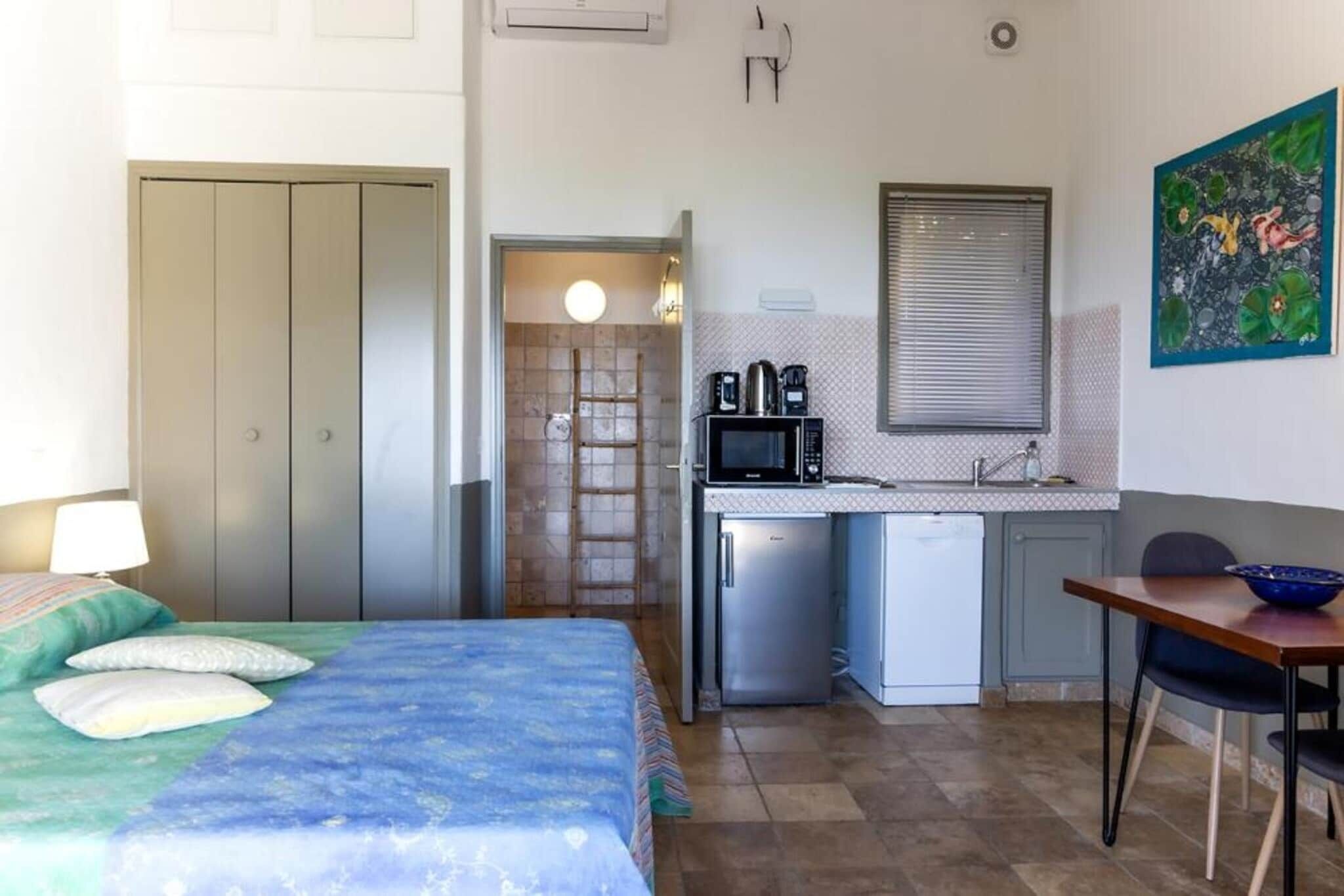Una camera da letto con un letto, una scrivania, un forno a microonde e angolo cottura.