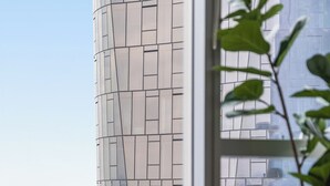 Een modern interieur met uitzicht op een stadsgezicht door een groot raam, met een hoog gebouw met een opvallend gevelontwerp.