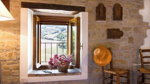 A rustic room with a stone wall, a window with open shutters, a wicker basket with flowers, and two wooden chairs. - Beautiful private villa for 6 people with WIFI, private pool, TV, patio and panoramic view (Tredozio)