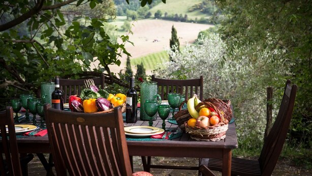 An outdoor dining table set with chairs, a basket of fruits, and green glassware. - Beautiful private villa for 6 people with WIFI, private pool, TV, patio and panoramic view (Tredozio)