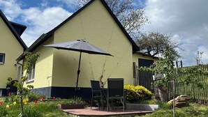 Um edifício amarelo com um pátio, área de estar ao ar livre e uma árvore.
