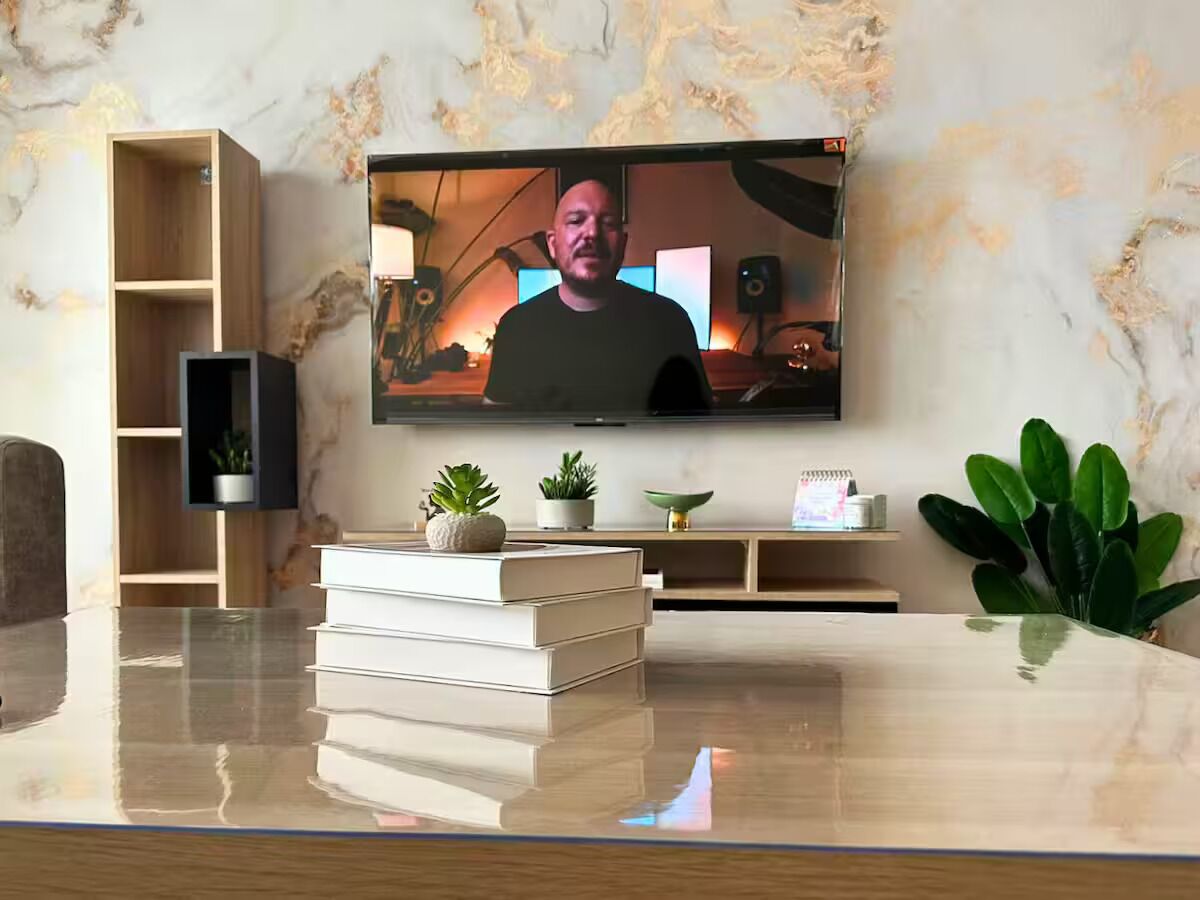 Un saló modern amb televisió de pantalla plana penjada a la paret, una taula baixa de fusta i una biblioteca amb objectes decoratius.
