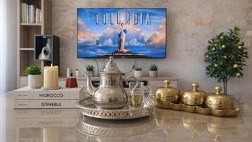A table with a tray of silver and gold tea sets, books titled 'Morocco', 'Istanbul', and 'Wobococo', and a TV displaying 'COLUMBIA'.